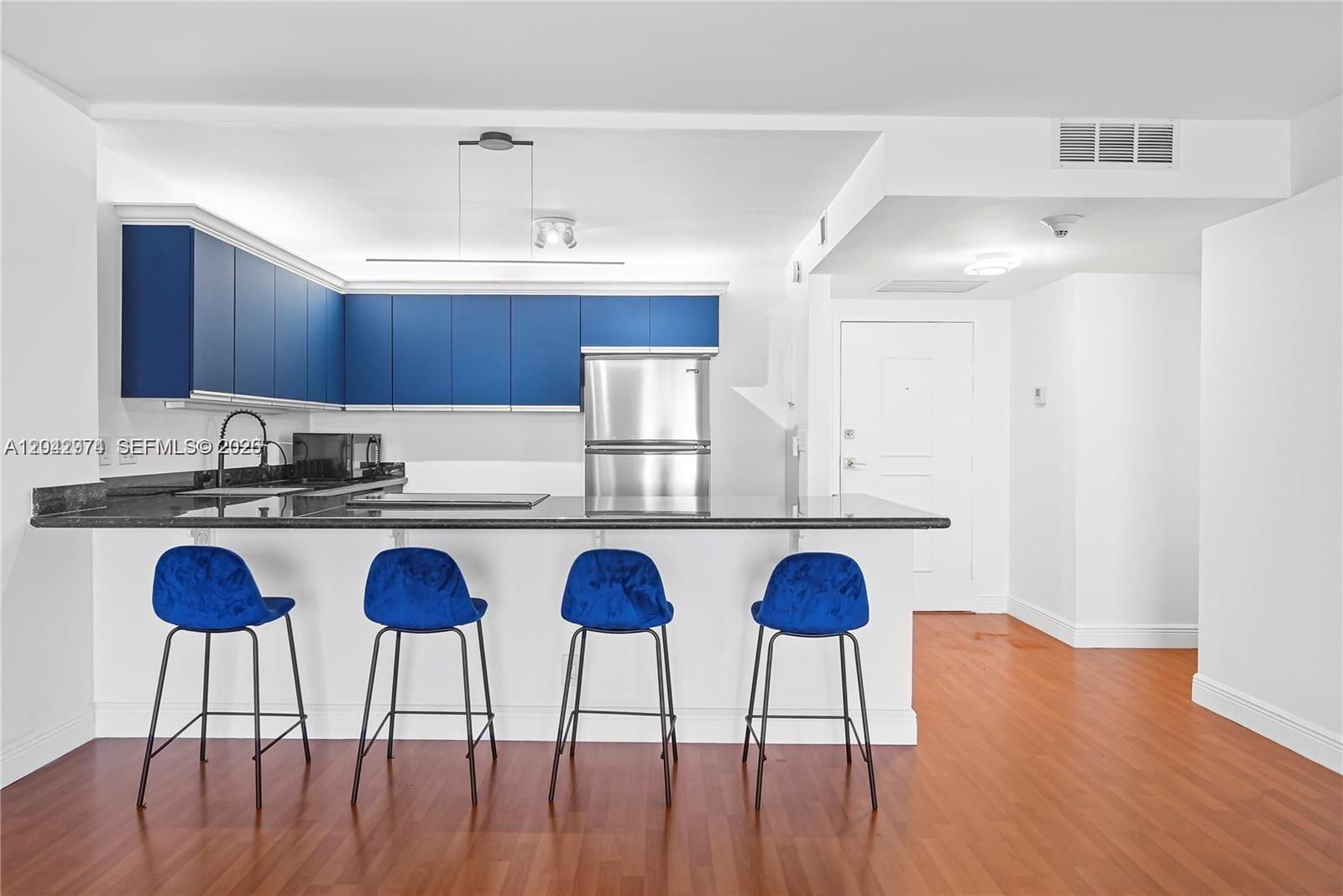 A kitchen features blue cabinets, a black countertop, and four blue bar stools — 2500 Parkview Dr # 1503, Hallandale Beach FL 33009, HALLANDALE BEACH, FL