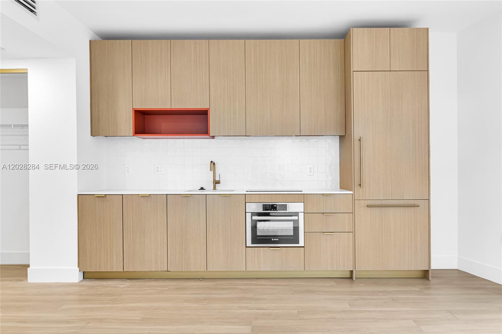 A modern kitchen features light wood cabinetry, a red open shelf, and stainless steel appliances — 90 NE 32 # 714, Miami FL 33127, MIAMI, FL
