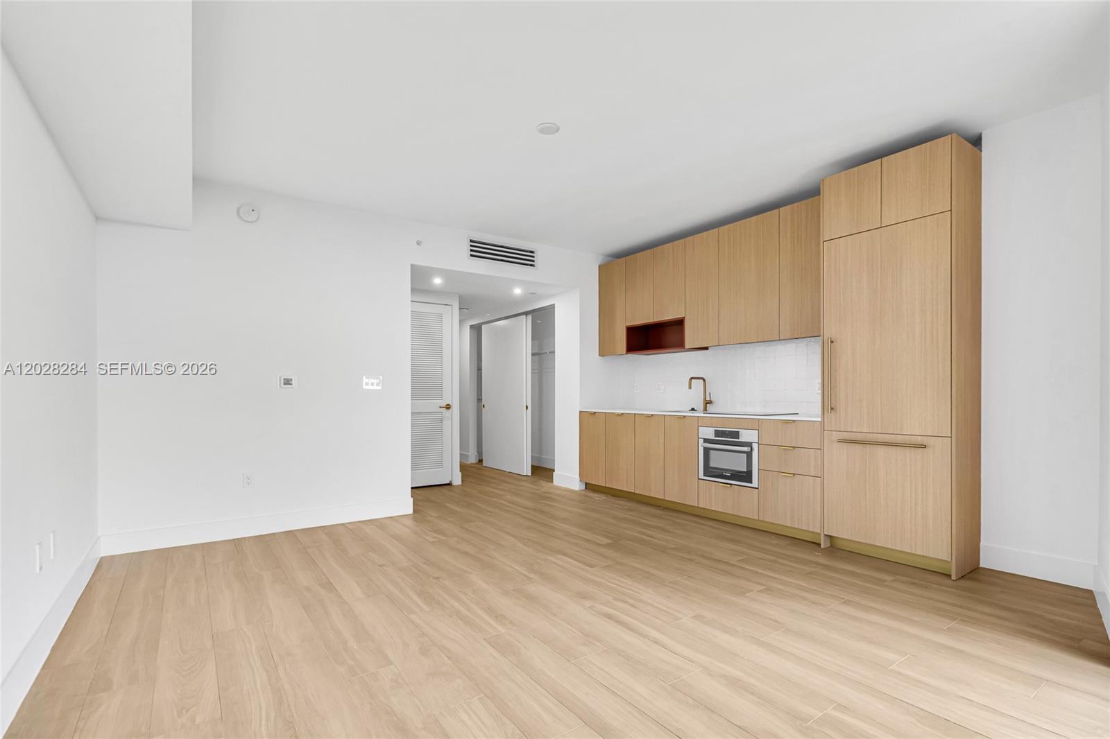 A modern kitchen features light wood cabinetry, a built-in oven, and light-colored flooring — 90 NE 32 # 714, Miami FL 33127, MIAMI, FL