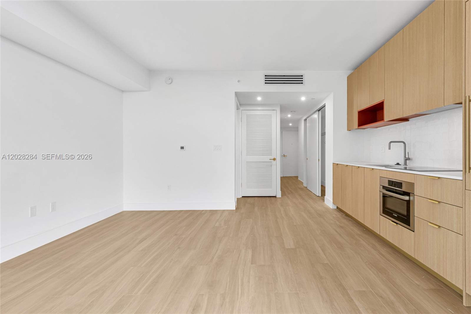 A modern kitchen features light wood cabinetry, white countertops, and stainless steel appliances — 90 NE 32 # 714, Miami FL 33127, MIAMI, FL