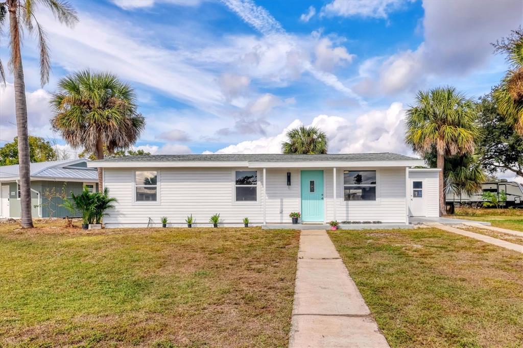 A single-story white house with a light blue front door and a concrete walkway — 22152 LARAMORE AVENUE, PORT CHARLOTTE, FL