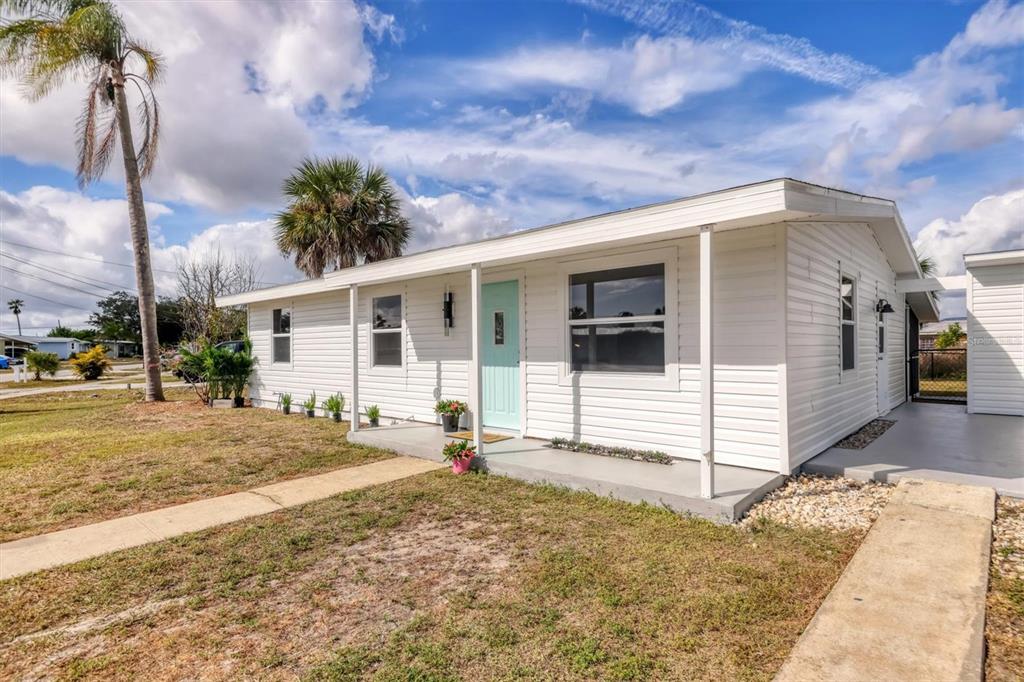 A white single-story house with a light blue front door and a covered porch — 22152 LARAMORE AVENUE, PORT CHARLOTTE, FL