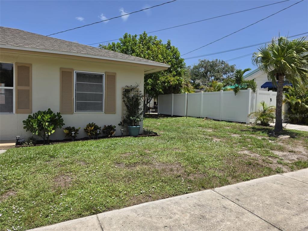 A side view of a house exterior with a white fence and a palm tree — 121 BAY STREET, TARPON SPRINGS, FL