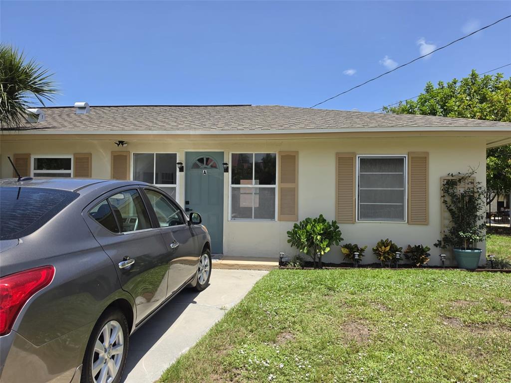 A single-story house exterior features a light-colored facade, a blue front door, and a parked car — 121 BAY STREET, TARPON SPRINGS, FL