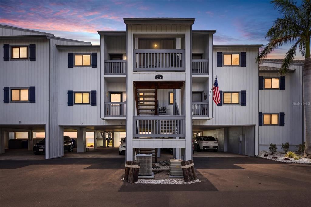 A three-story apartment building with elevated parking, exterior staircases, and balconies at dusk — 818 BAHIA DEL SOL DRIVE UNIT 28, RUSKIN, FL