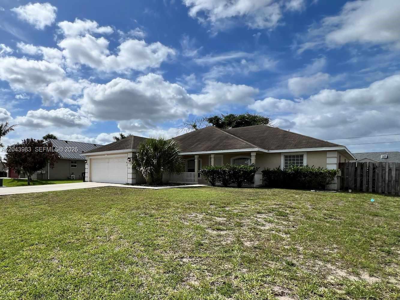 A single-story house with a tan exterior, a two-car garage, and a front porch — PORT ST. LUCIE, FL
