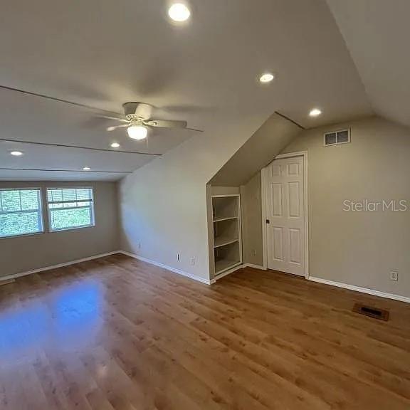 An attic bedroom features light wood flooring, a ceiling fan, recessed lighting, and built-in shelving — 875 S LAKE SHORE WAY, LAKE ALFRED, FL