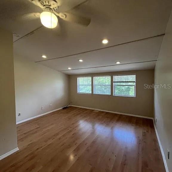 An empty room with wood-look flooring, a ceiling fan, recessed lighting, and three windows — 875 S LAKE SHORE WAY, LAKE ALFRED, FL