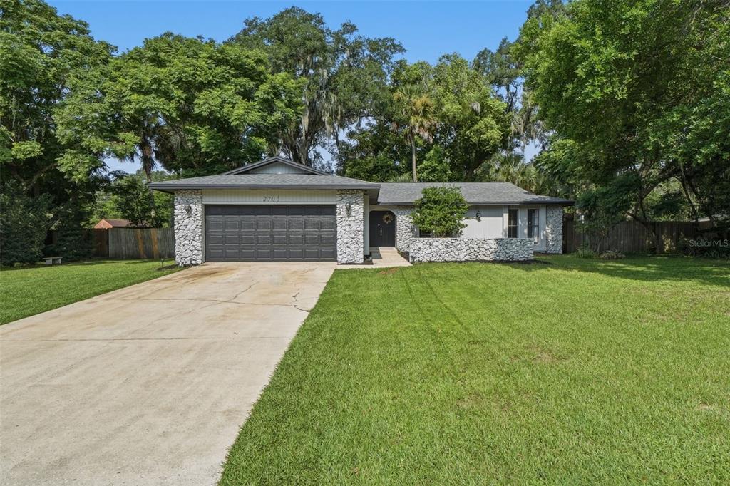 A single-story house with a stone facade, dark garage door, and a concrete driveway — 2700 CONCORD ROAD, DELAND, FL