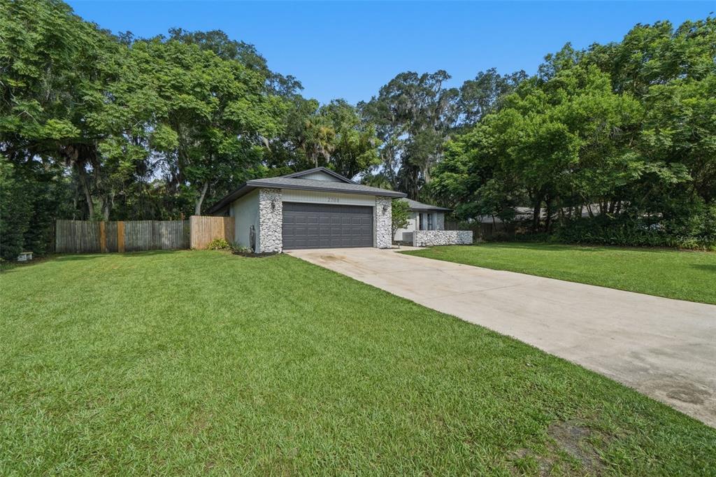 A single-story house with a stone facade, dark garage door, and a concrete driveway — 2700 CONCORD ROAD, DELAND, FL