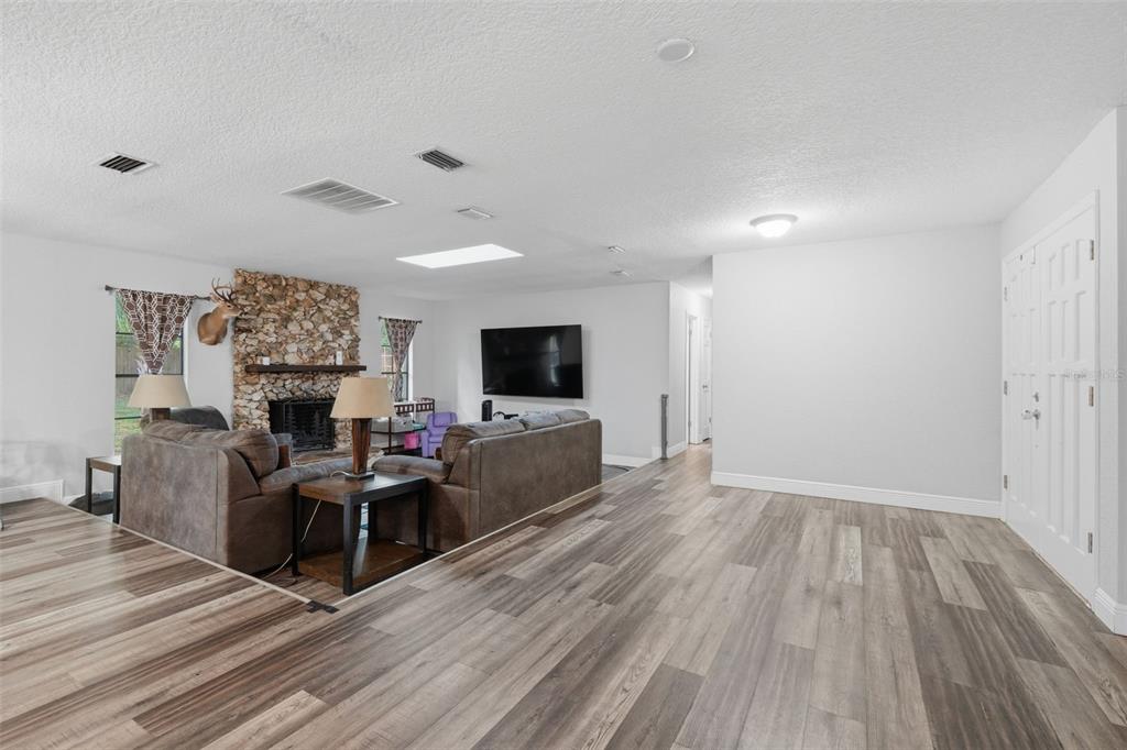 A living room features wood-look flooring, a stone fireplace, and a large wall-mounted television — 2700 CONCORD ROAD, DELAND, FL
