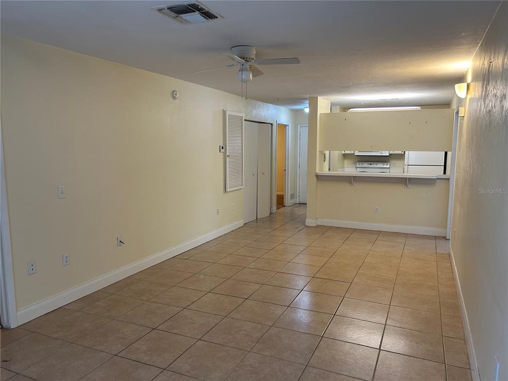 An open-concept living area with beige tile flooring, a ceiling fan, and a kitchen pass-through — 3800 SW 20TH AVENUE UNIT 501, GAINESVILLE, FL