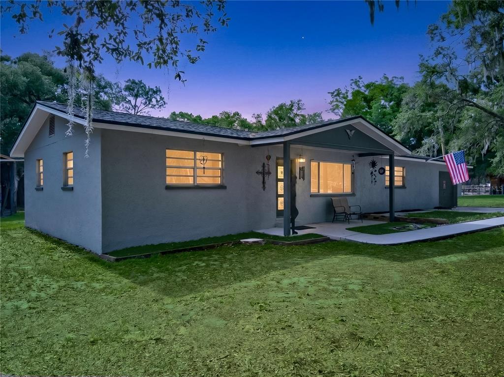 A single-story gray house with a covered porch and an American flag in the yard — 5304 TILLMAN ROAD, LAKELAND, FL