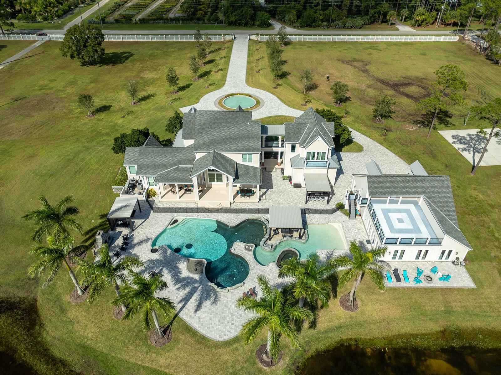An aerial view of a large house with a multi-section swimming pool and palm trees — 4236 Hield Road NW, Palm Bay FL 32907, PALM BAY, FL