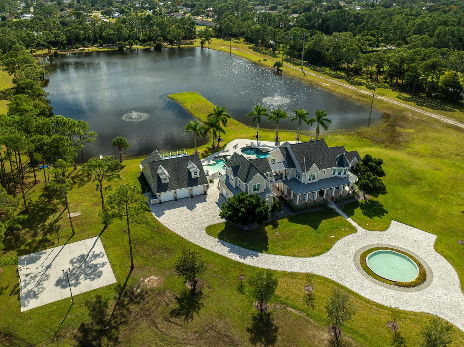 An aerial view of a large house with a pool, detached garage, and circular fountain — 4236 Hield Road NW, Palm Bay FL 32907, PALM BAY, FL