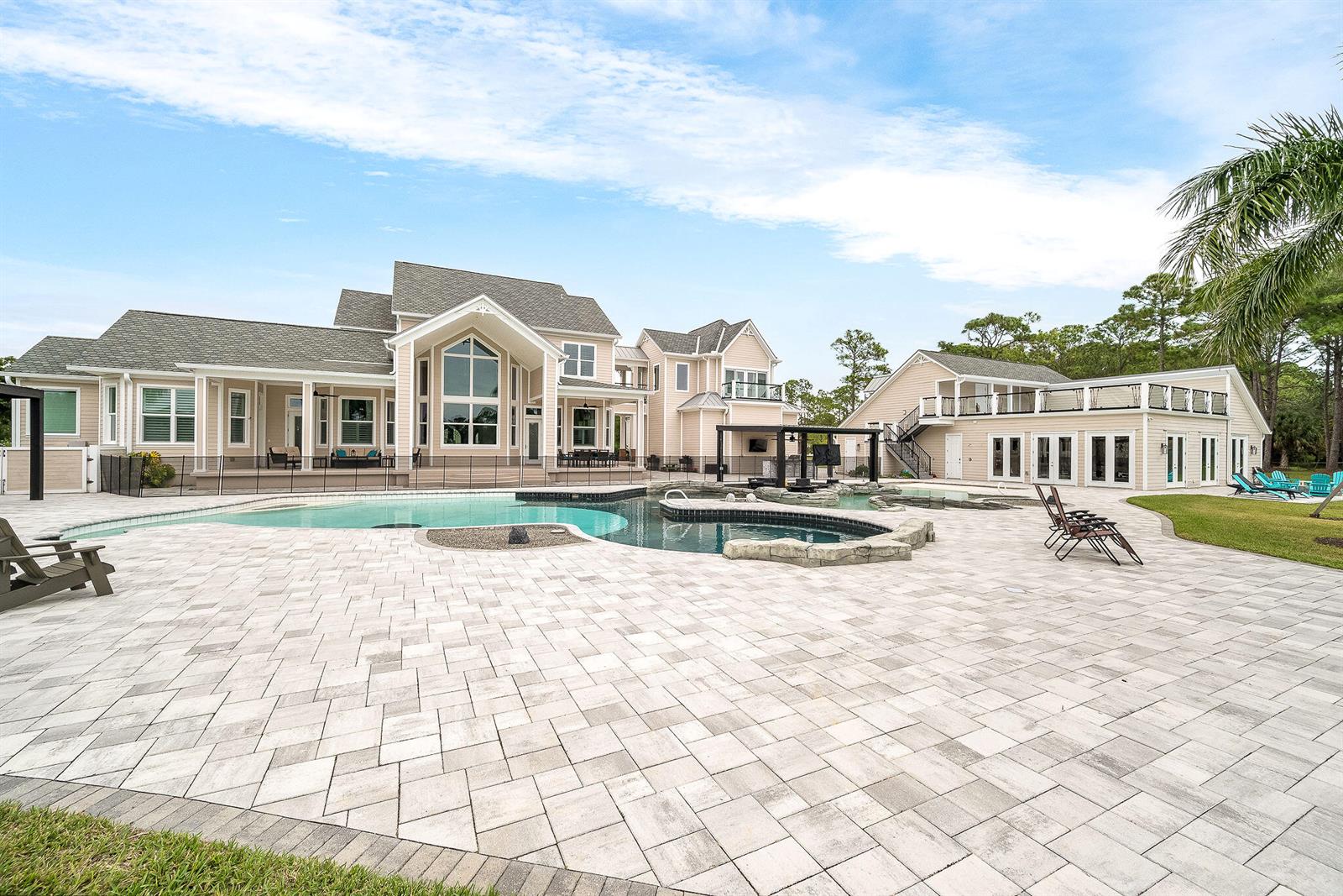 A large house with a pool, stone patio, and detached building under a blue sky — 4236 Hield Road NW, Palm Bay FL 32907, PALM BAY, FL
