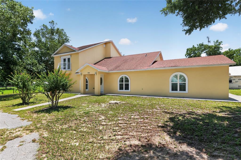 A two-story yellow house with a red shingled roof and arched windows — 3830 GRIFFIN VIEW DRIVE, LADY LAKE, FL