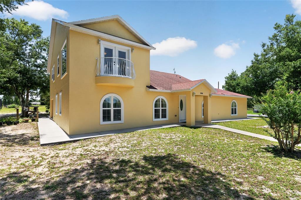 A two-story yellow stucco house features a balcony, arched windows, and a covered entryway — 3830 GRIFFIN VIEW DRIVE, LADY LAKE, FL