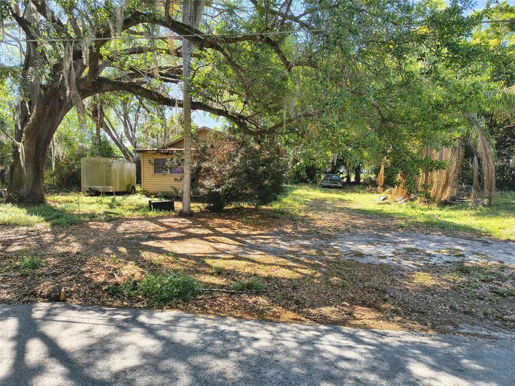 A small, weathered house sits on a wooded lot with a trailer and parked car — 3551 WASHINGTON STREET, SANFORD, FL