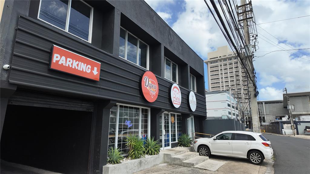 A two-story commercial building with a parking entrance, signage, and a white car parked outside — 133 O'NEILL ROAD, SAN JUAN, PR