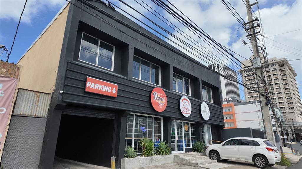 A two-story commercial building with a parking entrance, storefront signage, and a white parked car — 133 O'NEILL ROAD, SAN JUAN, PR