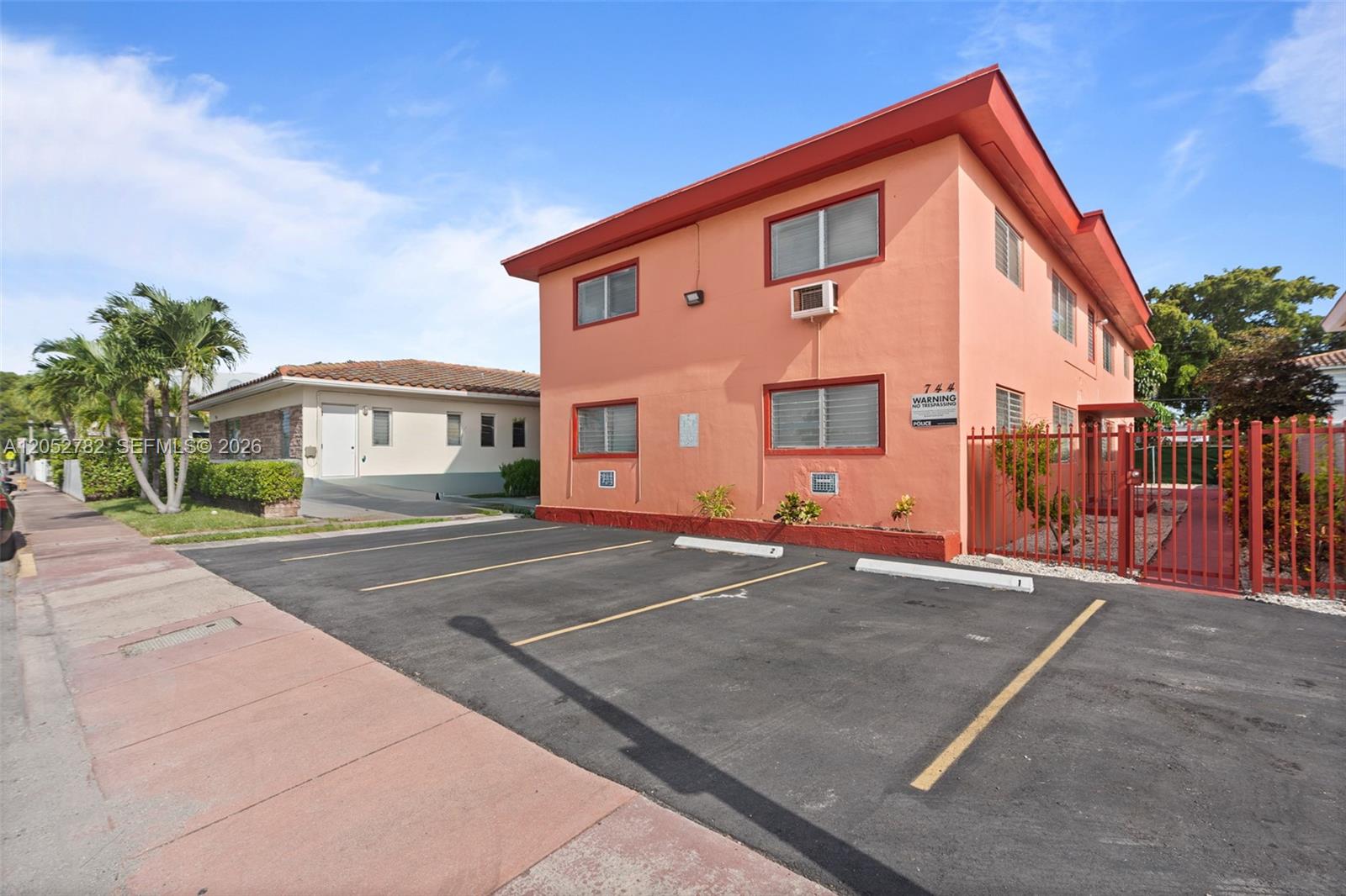 An exterior view of a two-story peach-colored apartment building with an adjacent parking lot — 744 85th St, Miami Beach FL 33141, MIAMI BEACH, FL