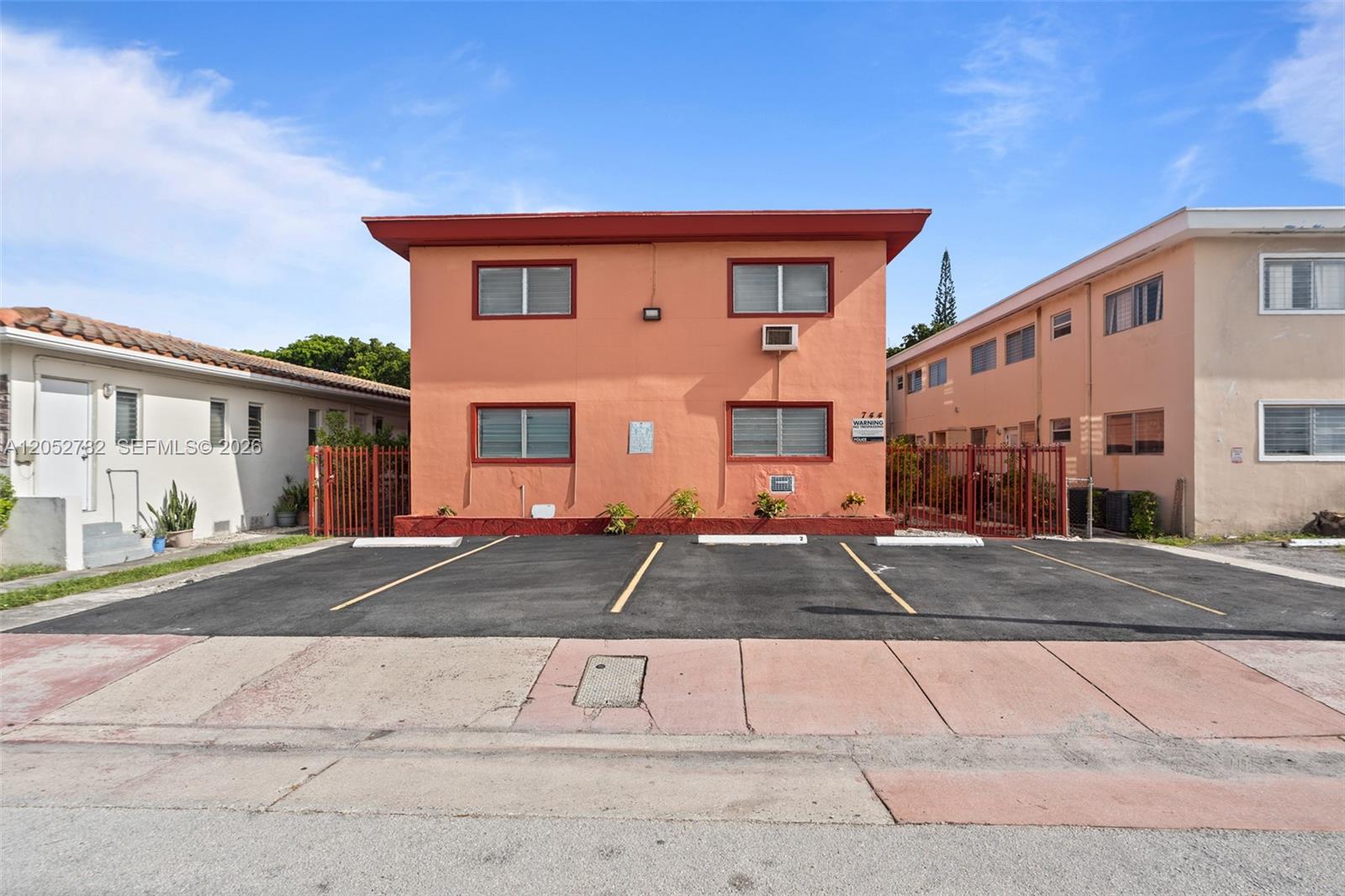 A two-story peach-colored apartment building features a paved parking lot in front — 744 85th St, Miami Beach FL 33141, MIAMI BEACH, FL