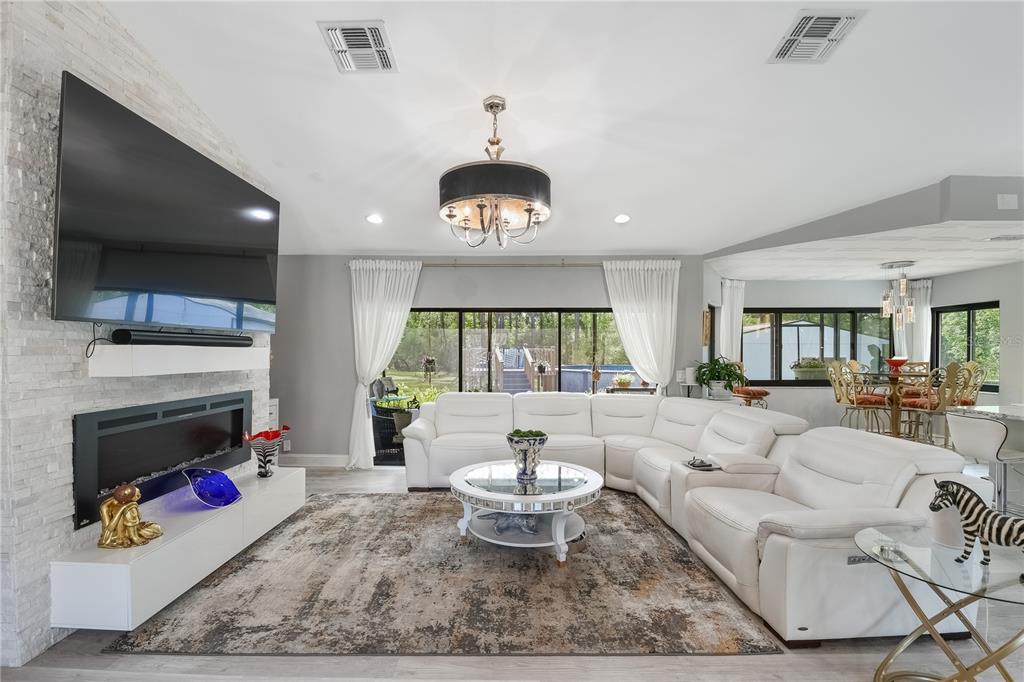 A living room features a white sectional sofa, a fireplace, and a large television — 2044 TUNISIA AVENUE, SPRING HILL, FL