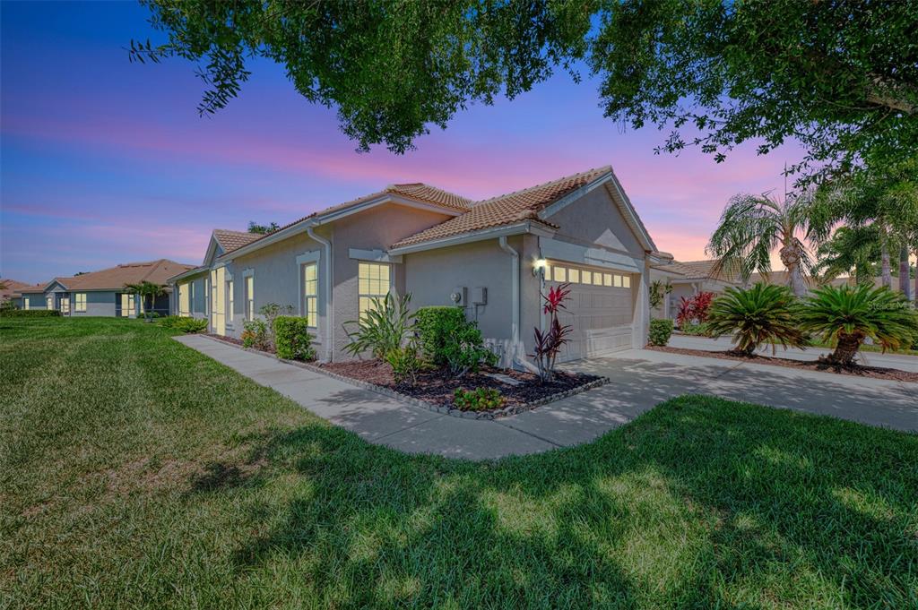 A single-story house with a beige stucco exterior and a tiled roof at sunset — 1842 SAN SILVESTRO DRIVE, VENICE, FL