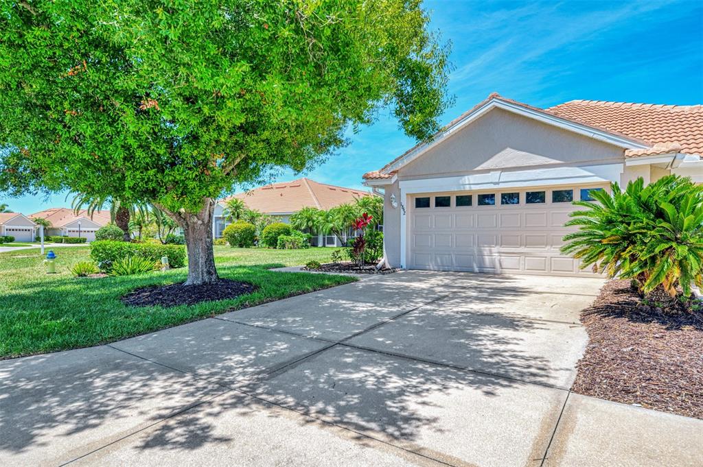 A suburban house features a concrete driveway, a two-car garage, and a large shade tree — 1842 SAN SILVESTRO DRIVE, VENICE, FL