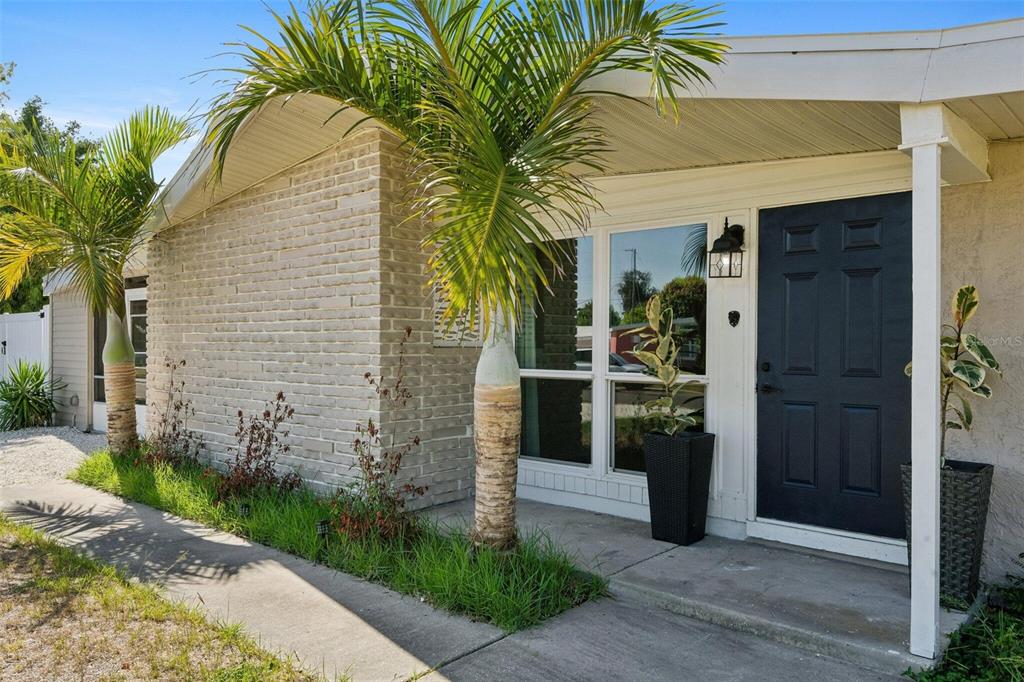 A brick-walled house exterior features a dark blue front door and two palm trees — 2416 EMORY AVENUE, BRADENTON, FL