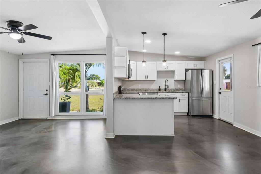 A kitchen with white cabinets, granite countertops, and stainless steel appliances opens to a living area — 2416 EMORY AVENUE, BRADENTON, FL