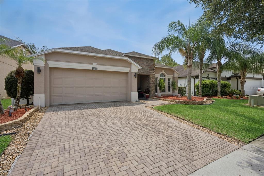 A single-story house with a beige stucco exterior, stone accents, and a paved driveway — 1519 BALSAM WILLOW TRAIL, ORLANDO, FL