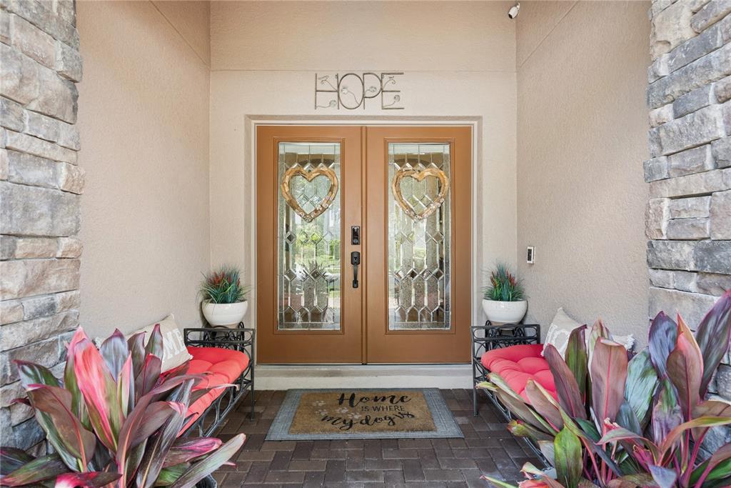 A front entryway features double glass doors, stone pillars, and two benches with red cushions — 1519 BALSAM WILLOW TRAIL, ORLANDO, FL