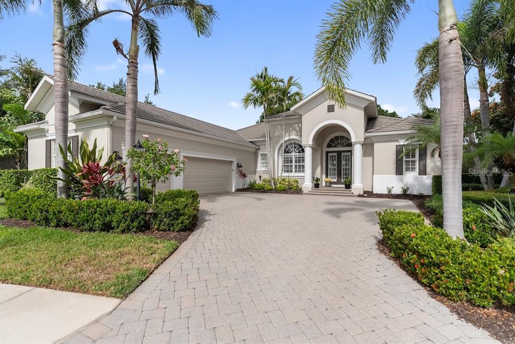 An open double door reveals a living room with wood floors and a pool view — 7312 GREYSTONE STREET, LAKEWOOD RANCH, FL
