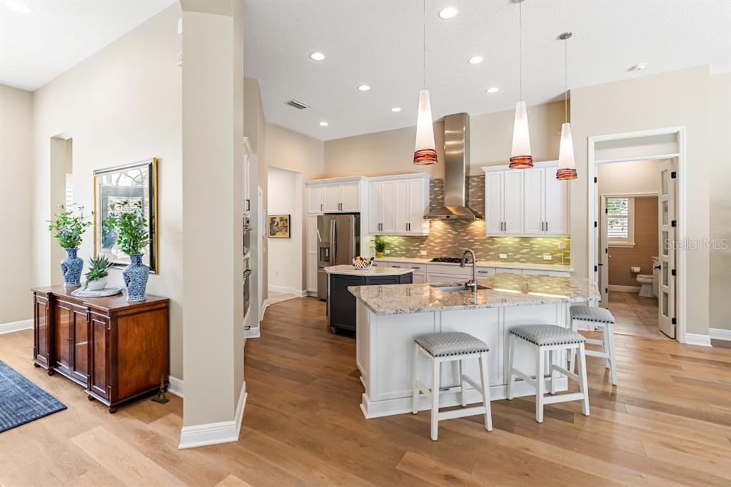 A living area features built-in shelves, two rattan chairs, and a sliding door to a pool — 7312 GREYSTONE STREET, LAKEWOOD RANCH, FL