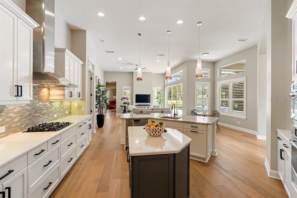A bright living area features built-in bookshelves, two rattan armchairs, and a view of the entryway — 7312 GREYSTONE STREET, LAKEWOOD RANCH, FL