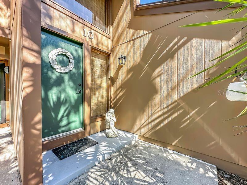 A green front door with a wreath and a small statue sits on a concrete porch — 10 OAKMONT COURT UNIT 10, PALM COAST, FL