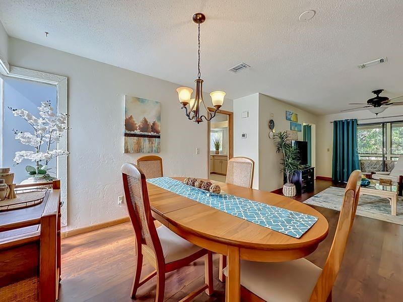 A dining room features a wooden table, a chandelier, and a view into the living area — 10 OAKMONT COURT UNIT 10, PALM COAST, FL