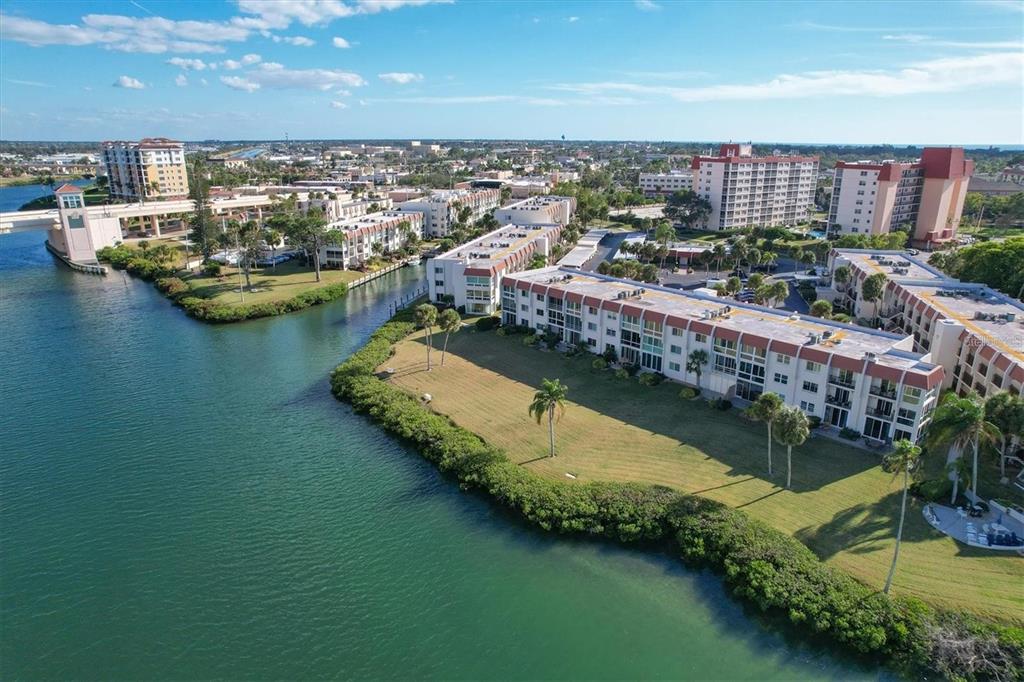 An aerial view of waterfront apartment buildings surrounded by green lawns and palm trees — 250 SANTA MARIA STREET UNIT 219, VENICE, FL