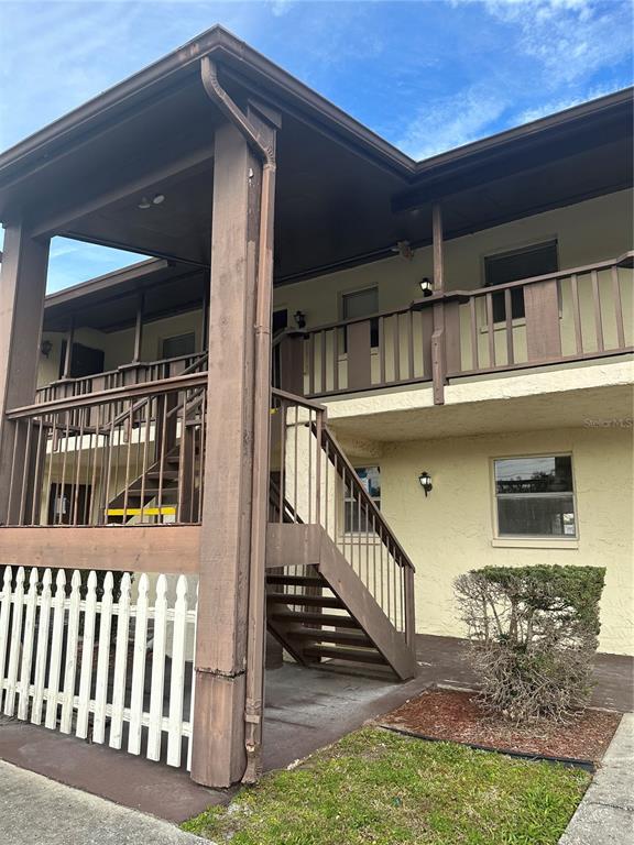 An exterior view of a two-story apartment building with wooden stairs and balcony railings — 8440 OLD POST ROAD UNIT 202, PORT RICHEY, FL