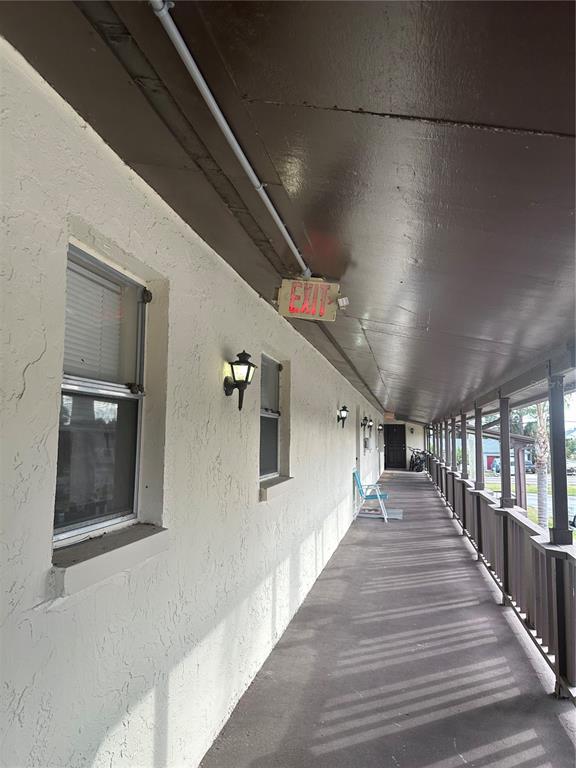 An exterior walkway features a covered porch, wall-mounted lanterns, and an illuminated exit sign — 8440 OLD POST ROAD UNIT 202, PORT RICHEY, FL