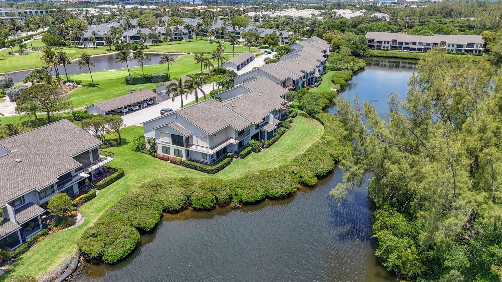 An aerial view shows multi-story apartment buildings situated along a lake and golf course — 2104 Fairway Drive S, Jupiter FL 33477, JUPITER, FL