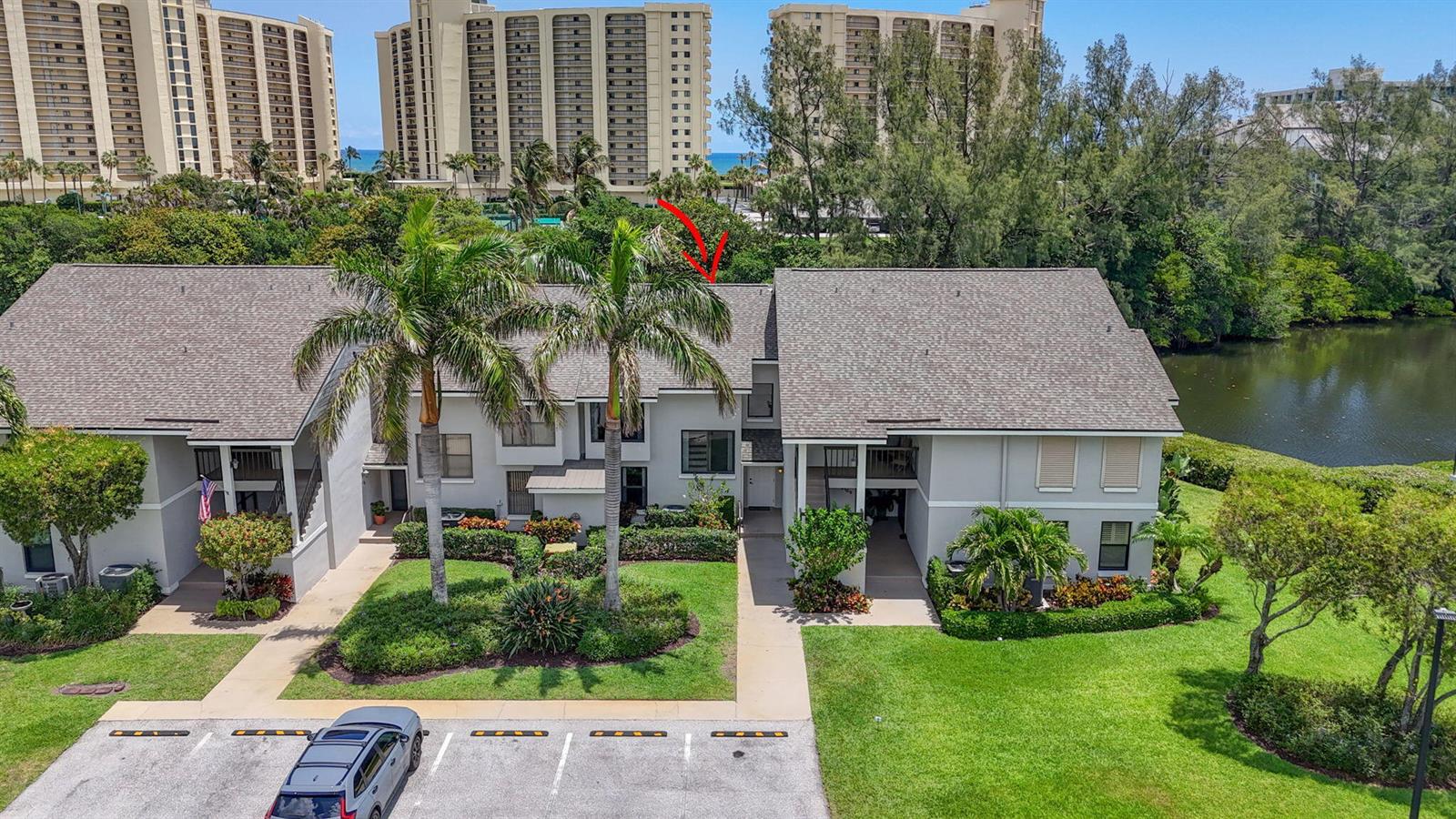 An aerial view of a two-story residential building with palm trees and a parking lot — 2104 Fairway Drive S, Jupiter FL 33477, JUPITER, FL