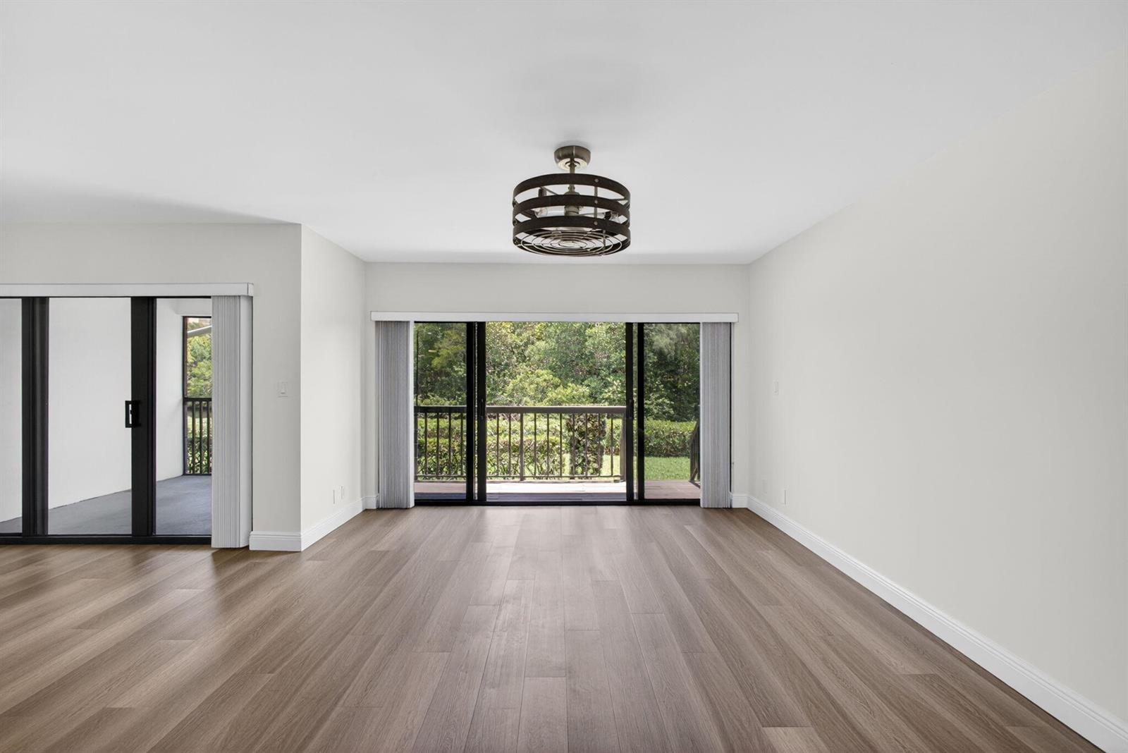 An empty room with light wood flooring, a ceiling fan, and sliding glass doors — 2104 Fairway Drive S, Jupiter FL 33477, JUPITER, FL