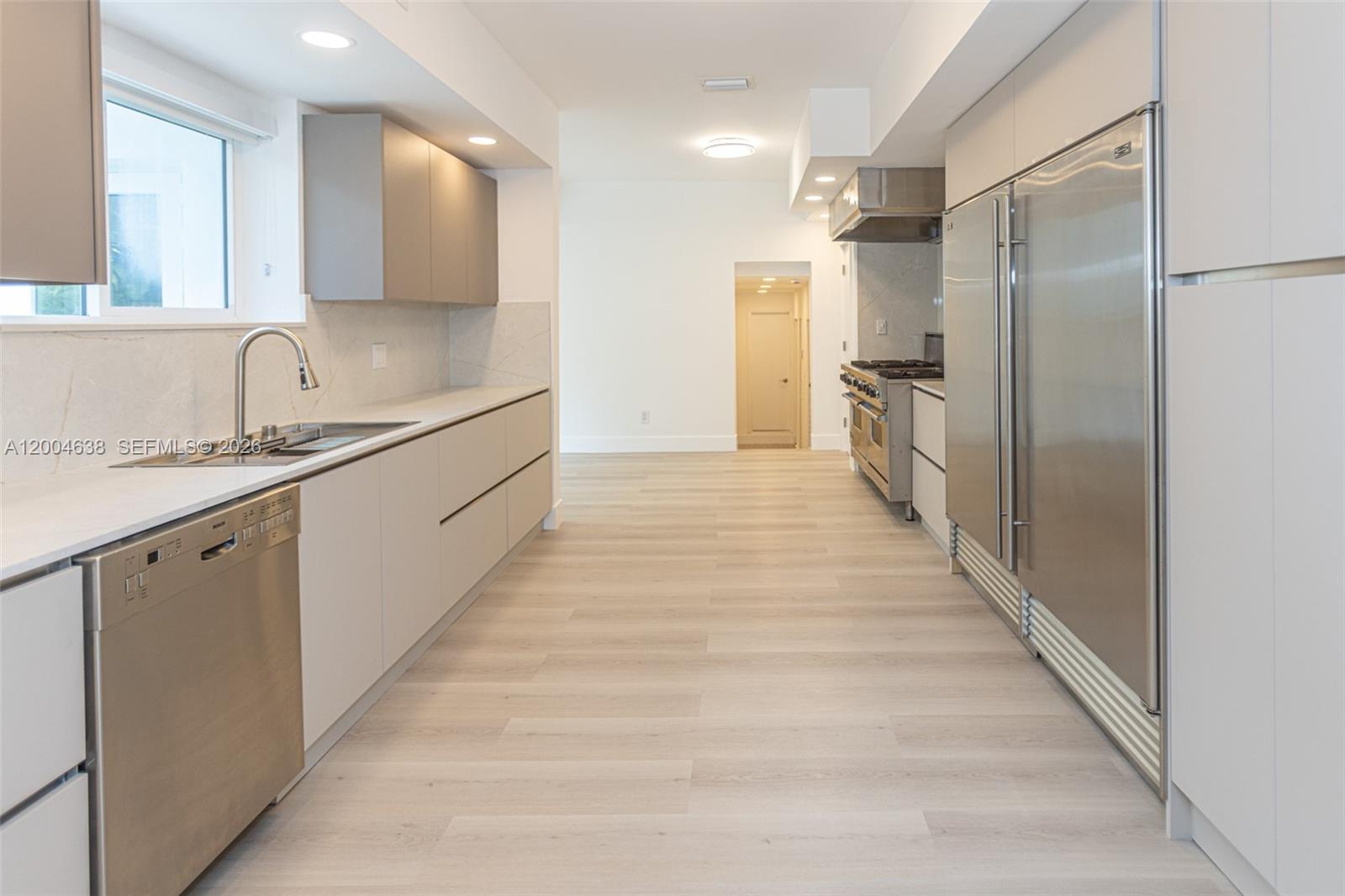 A modern kitchen features stainless steel appliances, light-colored cabinetry, and wood-look flooring — 1690 Daytonia Rd, Miami Beach FL 33141, MIAMI BEACH, FL