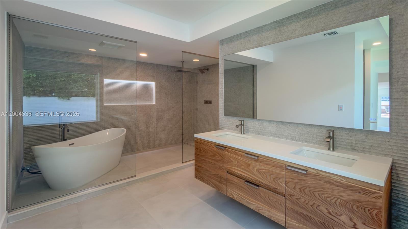 A modern bathroom features a floating wood vanity, a soaking tub, and a glass-enclosed shower — 1690 Daytonia Rd, Miami Beach FL 33141, MIAMI BEACH, FL