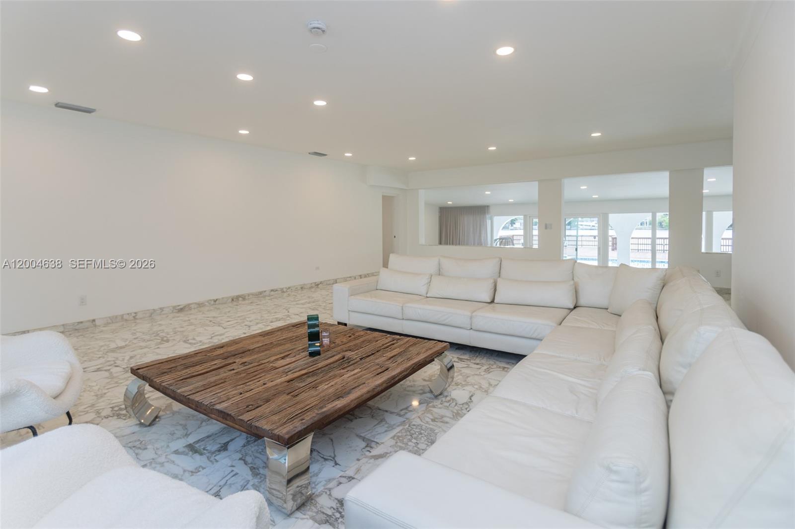 A living room features white leather sectional seating, a rustic wooden coffee table, and marble flooring — 1690 Daytonia Rd, Miami Beach FL 33141, MIAMI BEACH, FL