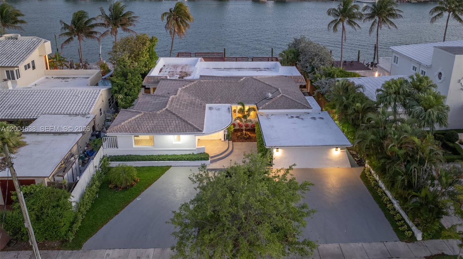 An aerial view shows a white waterfront house with a tiled roof and paved driveway — 1690 Daytonia Rd, Miami Beach FL 33141, MIAMI BEACH, FL