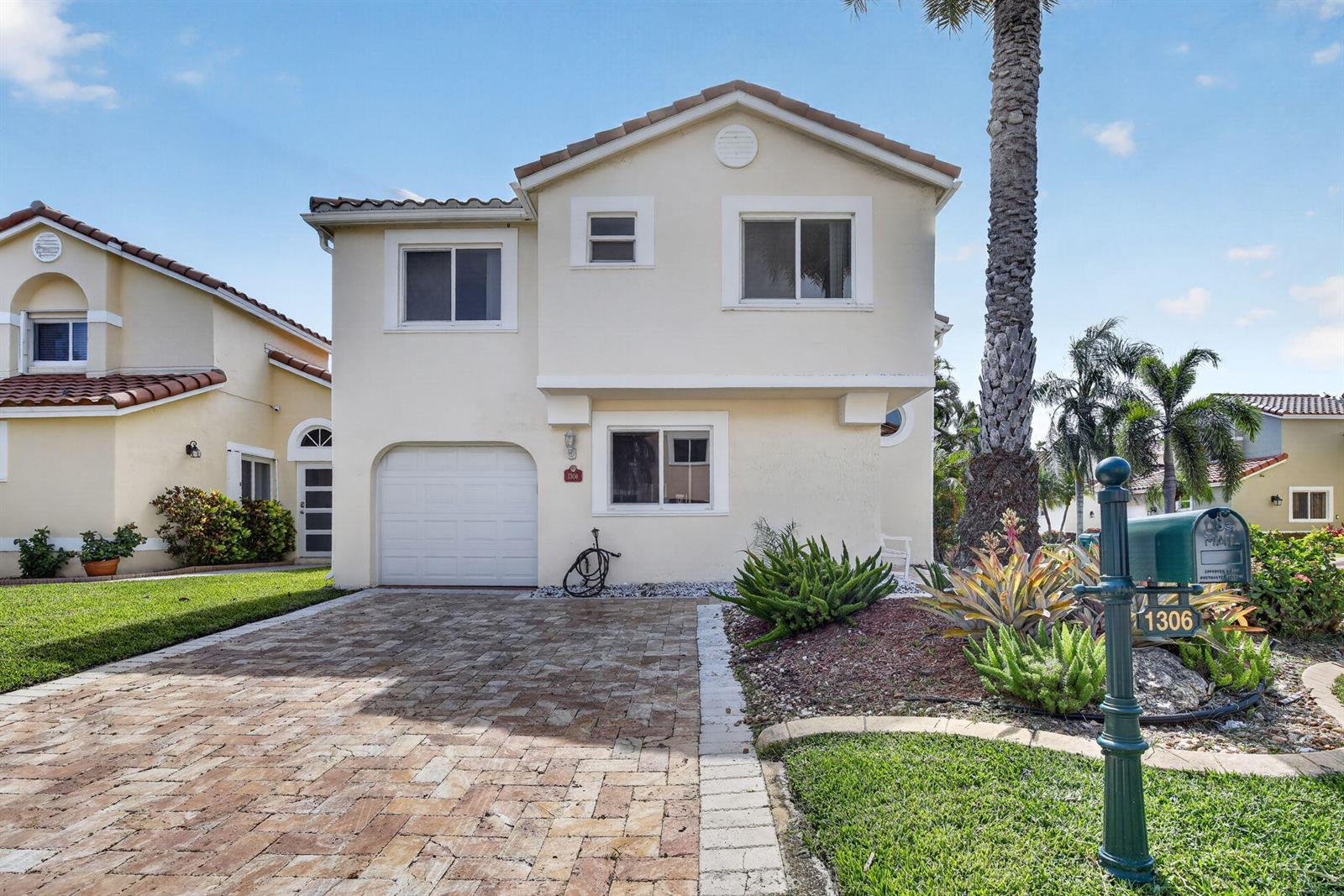 A two-story house with a paved driveway, garage, and a green mailbox in the foreground — 1306 SE 5th Court, Dania Beach FL 33004, DANIA BEACH, FL